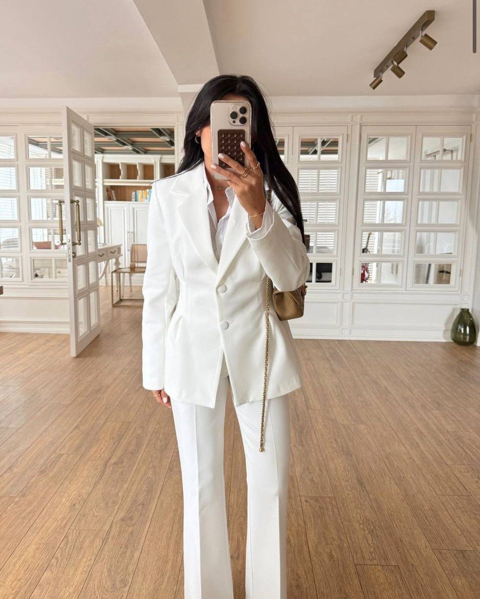 13 Going on 30 Outfits: 6 Ideas to Recreate the Iconic Style 4 Woman in a structured white blazer and white trousers taking a mirror selfie.