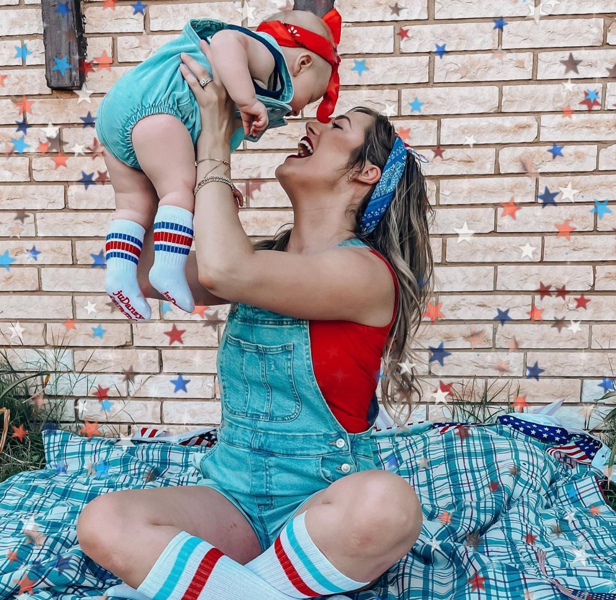 4th of July Outfits: 8 Festive Looks for Women 4 Woman and baby wearing red, white, and blue outfits sitting on a plaid blanket.