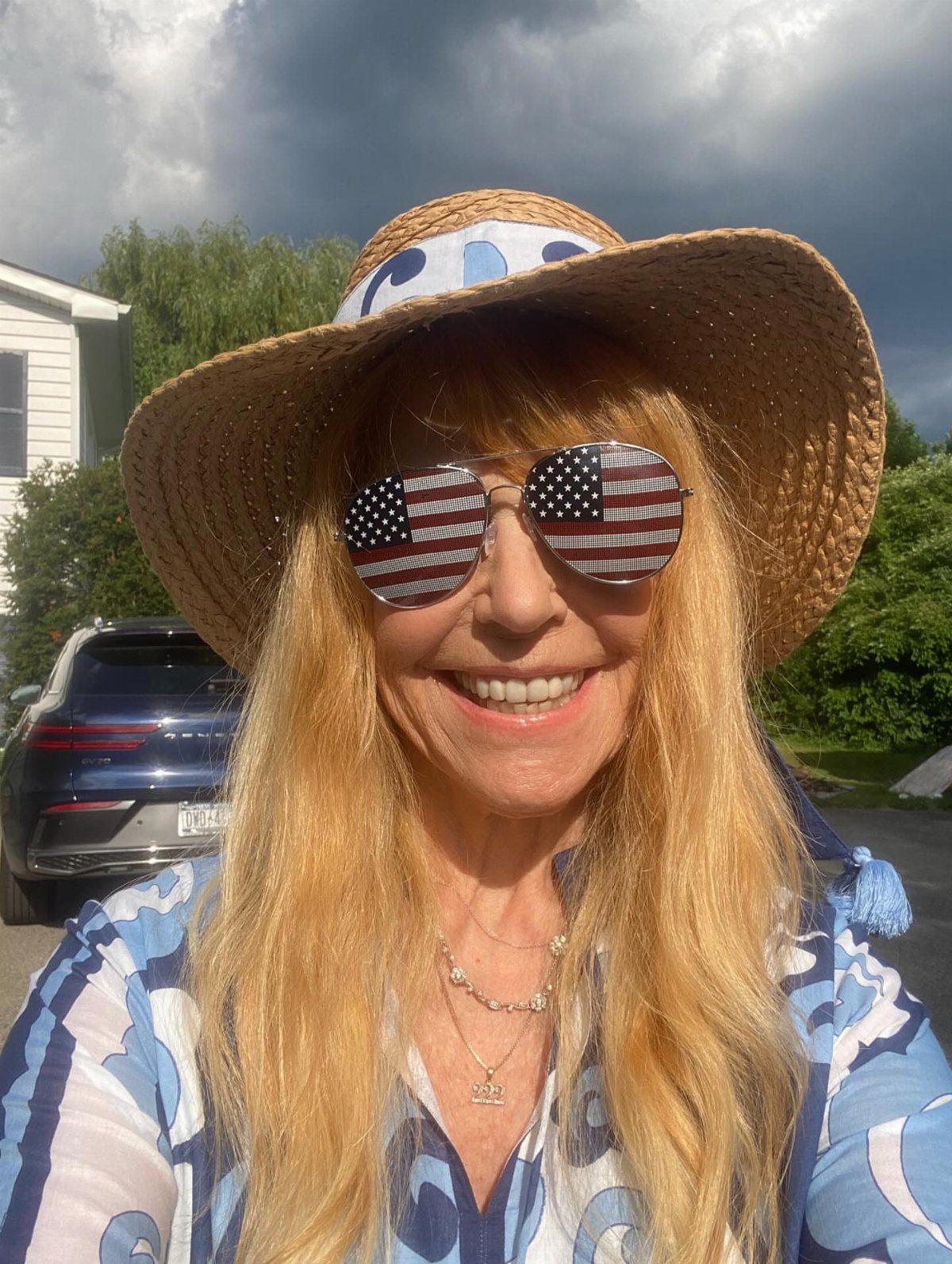 4th of July Outfits: 8 Festive Looks for Women 7 Woman wearing American flag sunglasses and a straw hat for Fourth of July.