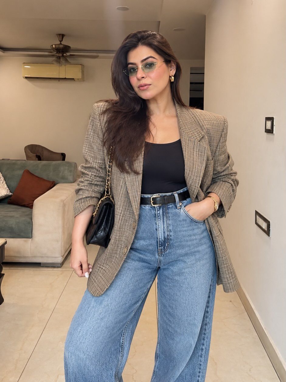 80s Inspired Outfits: 8 Bold Looks to Recreate the Decade 3 Woman wearing a brown bold-shoulder blazer with high-waisted wide-leg blue jeans.