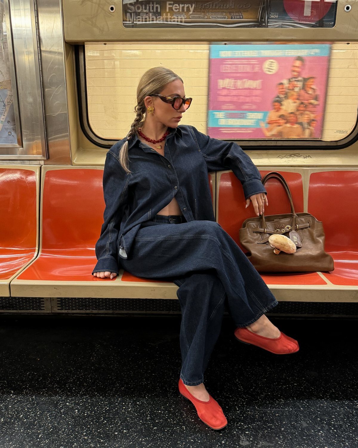 Woman in double denim outfit wearing a red beaded choker necklace on a subway.