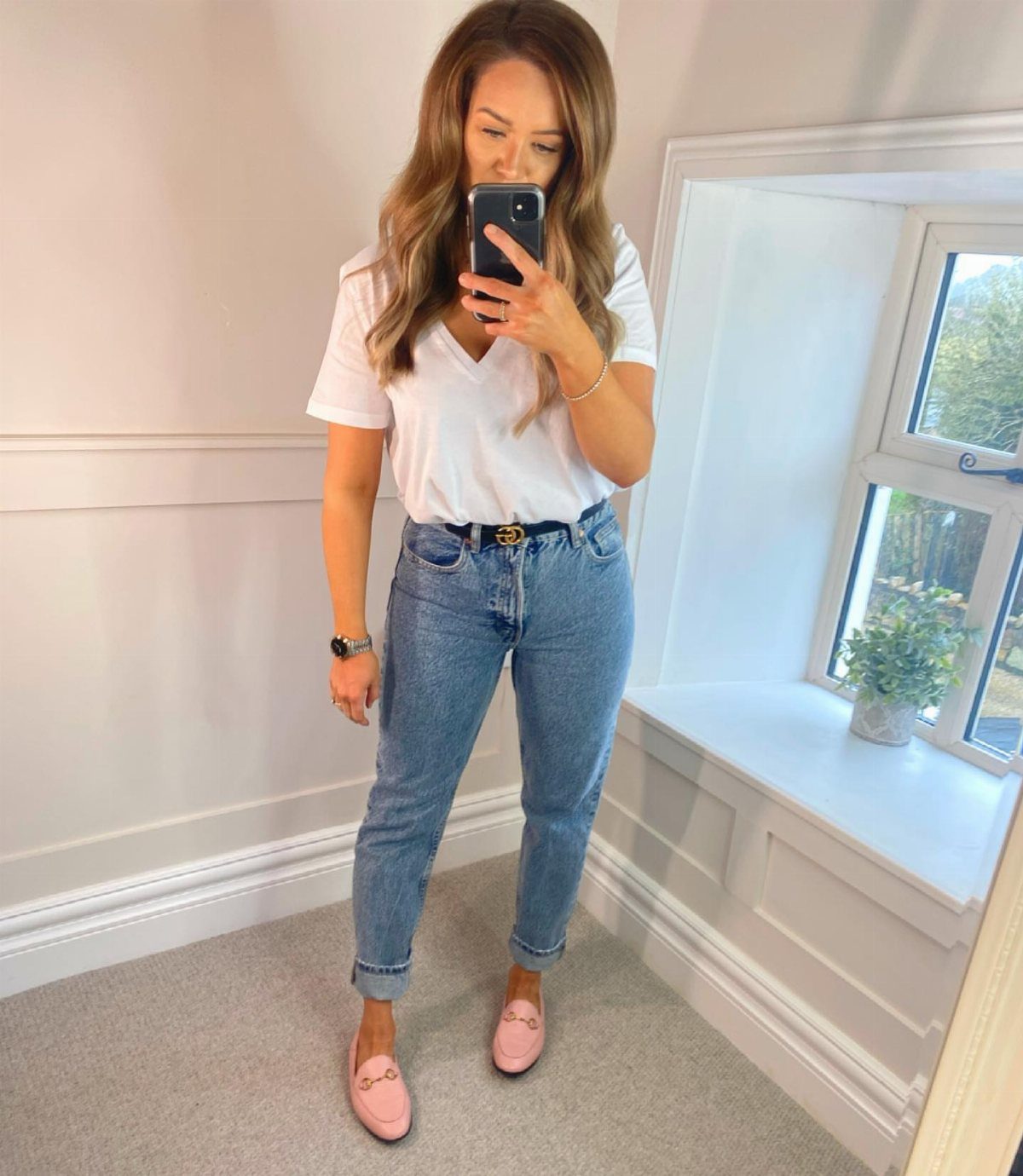 Woman wearing high-waisted blue mom jeans, white t-shirt, and pink loafers.