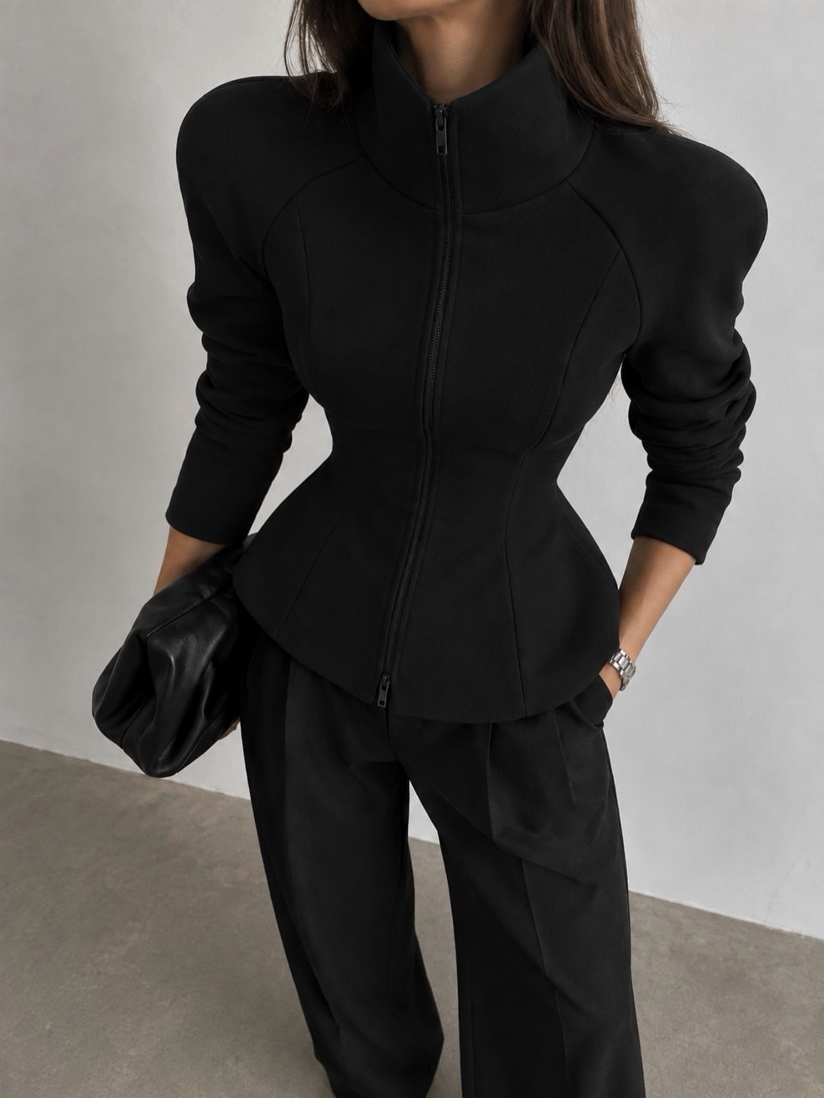 Apple Body Shape Outfits That Flatter Your Figure (9 Ideas) 7 Person wearing a structured black zip-up jacket and black trousers with a clutch bag.