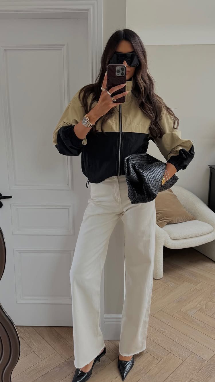 Apple Body Shape Outfits That Flatter Your Figure (9 Ideas) 4 Woman in two-tone zip-up jacket and wide-leg white trousers taking a mirror selfie.