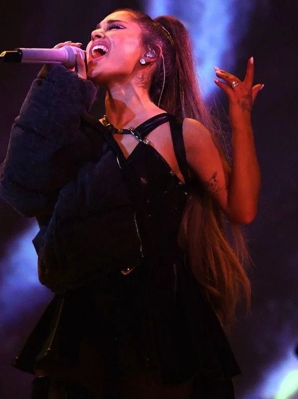 Ariana Grande Concert Outfits: 12 Looks for 2026 Shows 11 Ariana Grande singing on stage wearing a black concert outfit and high ponytail