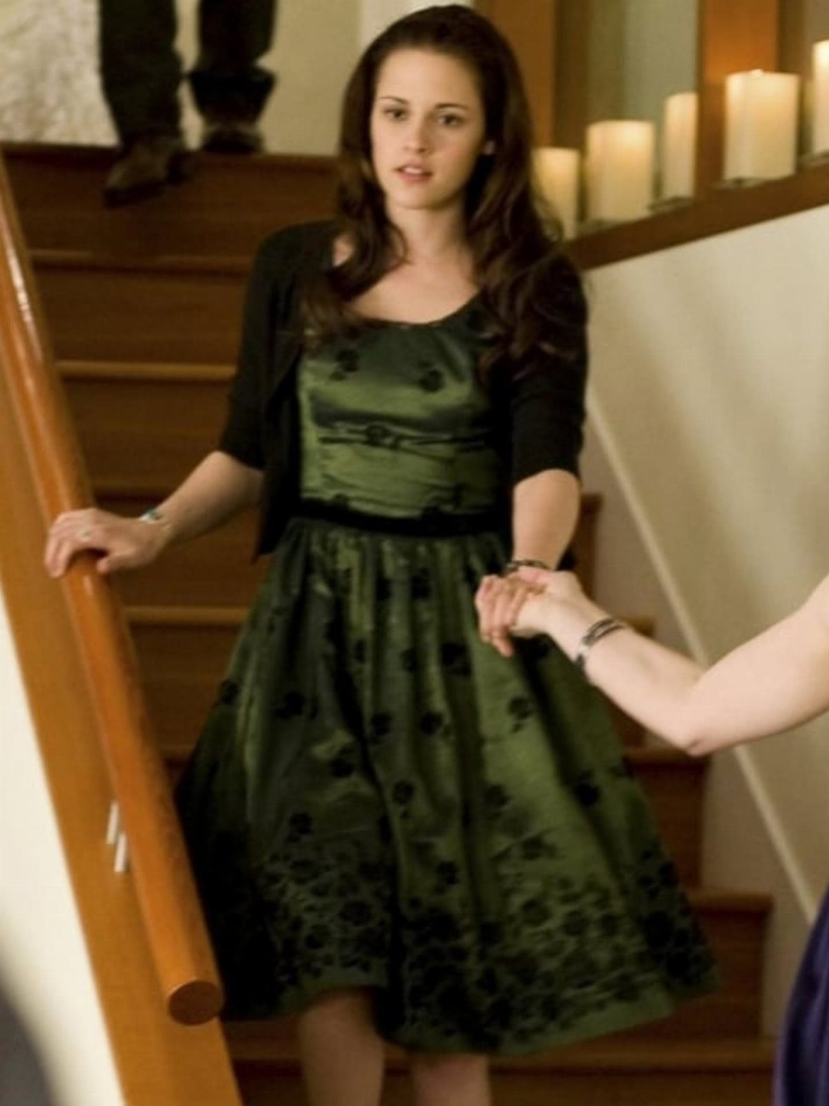 Bella Swan Outfits: 10 Iconic Looks from the Twilight Saga 4 Woman wearing a green floral dress and black cardigan standing on wooden stairs.