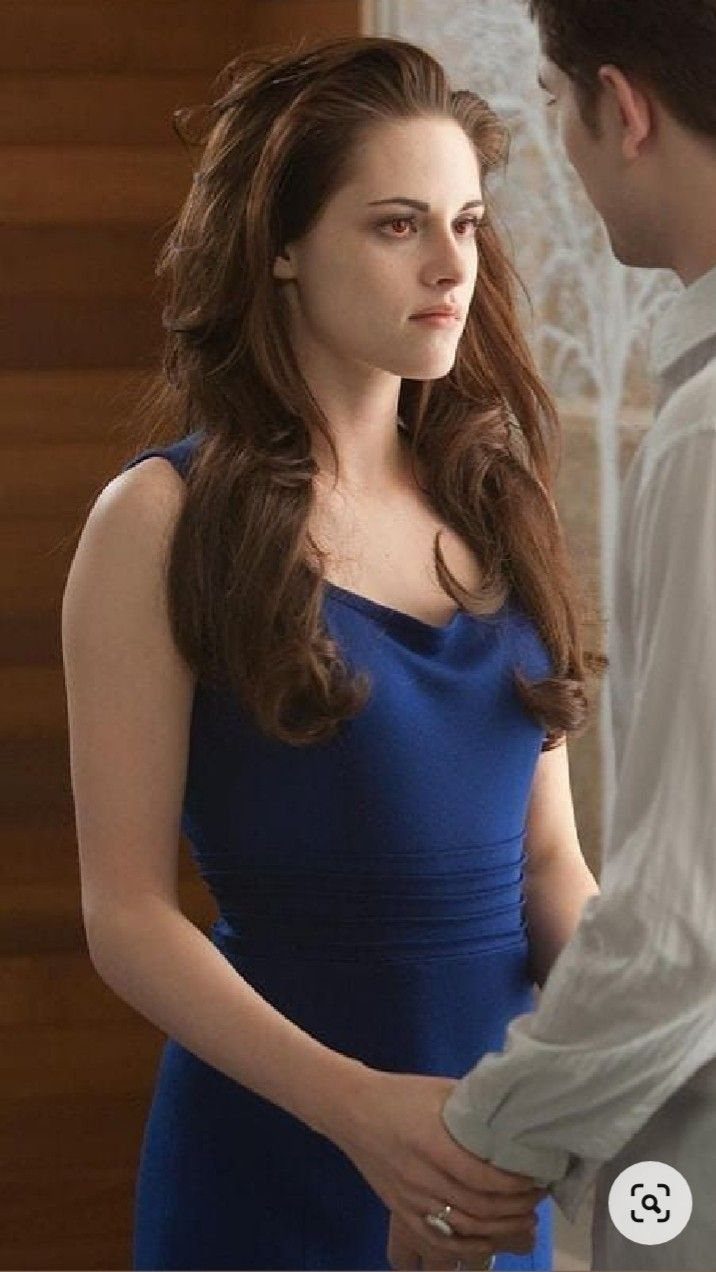 Bella Swan Outfits: 10 Iconic Looks from the Twilight Saga 6 Woman in a royal blue dress with a draped neckline standing with a man.