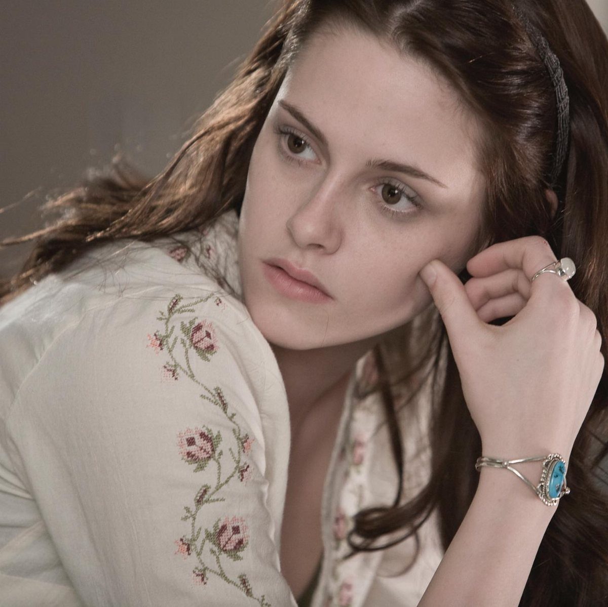 Bella Swan Outfits: 10 Iconic Looks from the Twilight Saga 9 Young woman with brown hair wearing a cream floral embroidered blouse and jewelry.