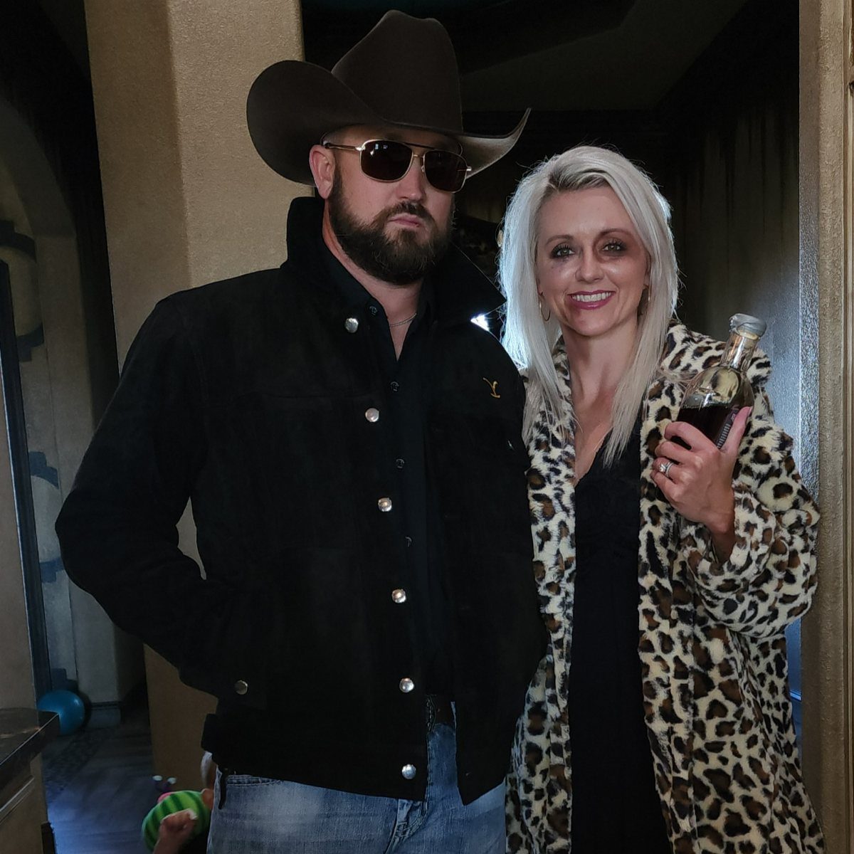 Beth Dutton Outfits: 12 Looks from Yellowstone's Style Icon 5 Woman in leopard print coat and man in cowboy hat posing together.