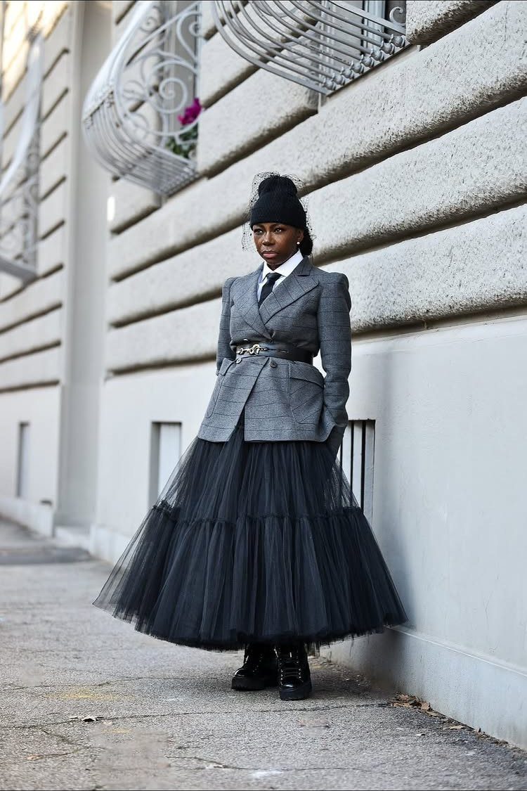 Black woman wearing a grey blazer and a large black tulle skirt outdoors.