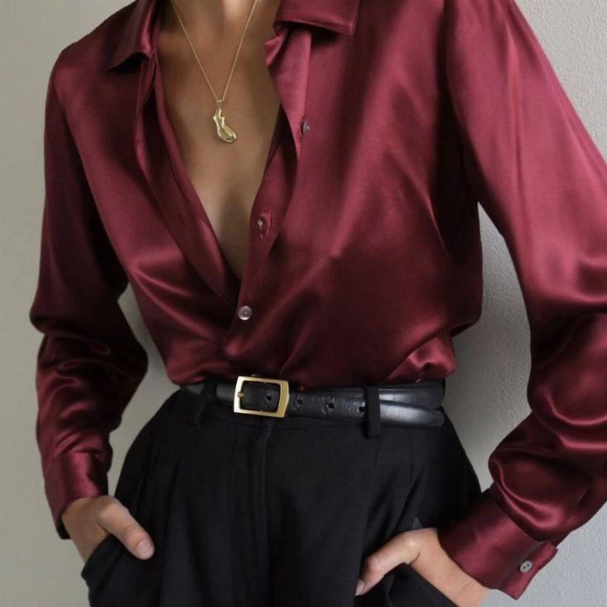 7 Burgundy Outfits for Women to Wear This Season 5 Burgundy satin shirt tucked into black trousers with a black leather belt.