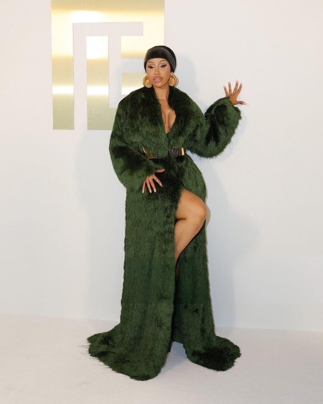 Cardi B Concert Outfits: 9 Bold Looks to Turn Heads 7 Cardi B wearing a long dark green faux fur coat and gold hoop earrings.