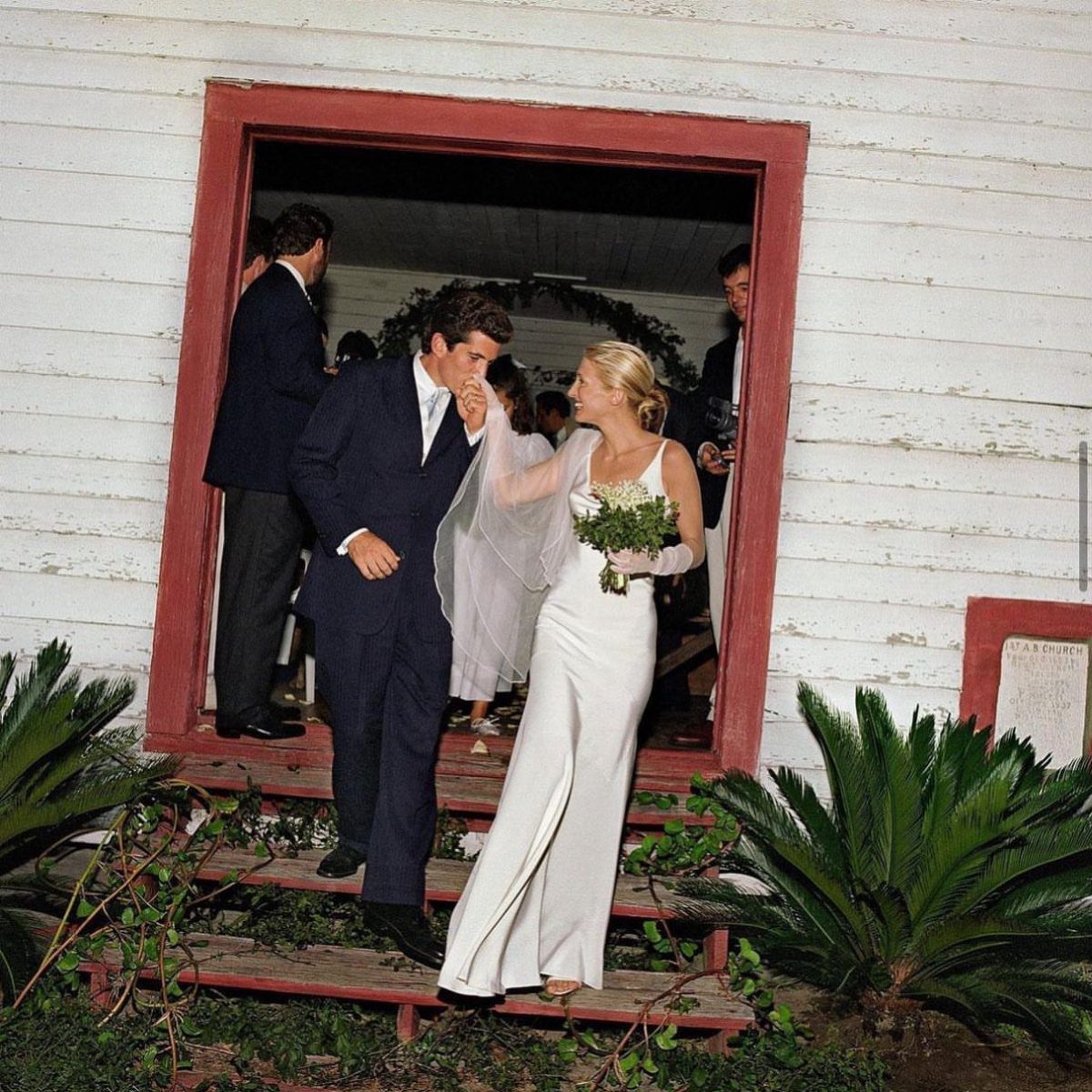 13 Carolyn Bessette Outfits You Can Actually Wear Today 5 Woman in a minimalist white wedding gown and man in a navy suit.