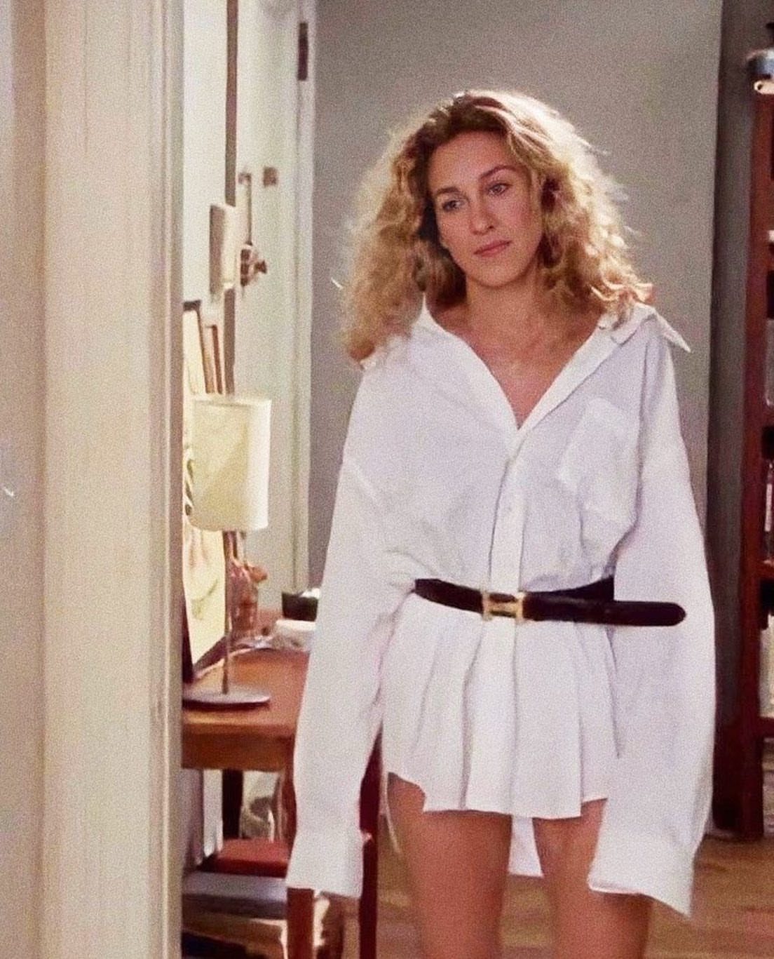Carrie Bradshaw Outfits: 11 Iconic Looks to Recreate 5 Woman with curly blonde hair wearing an oversized white shirt and black belt.
