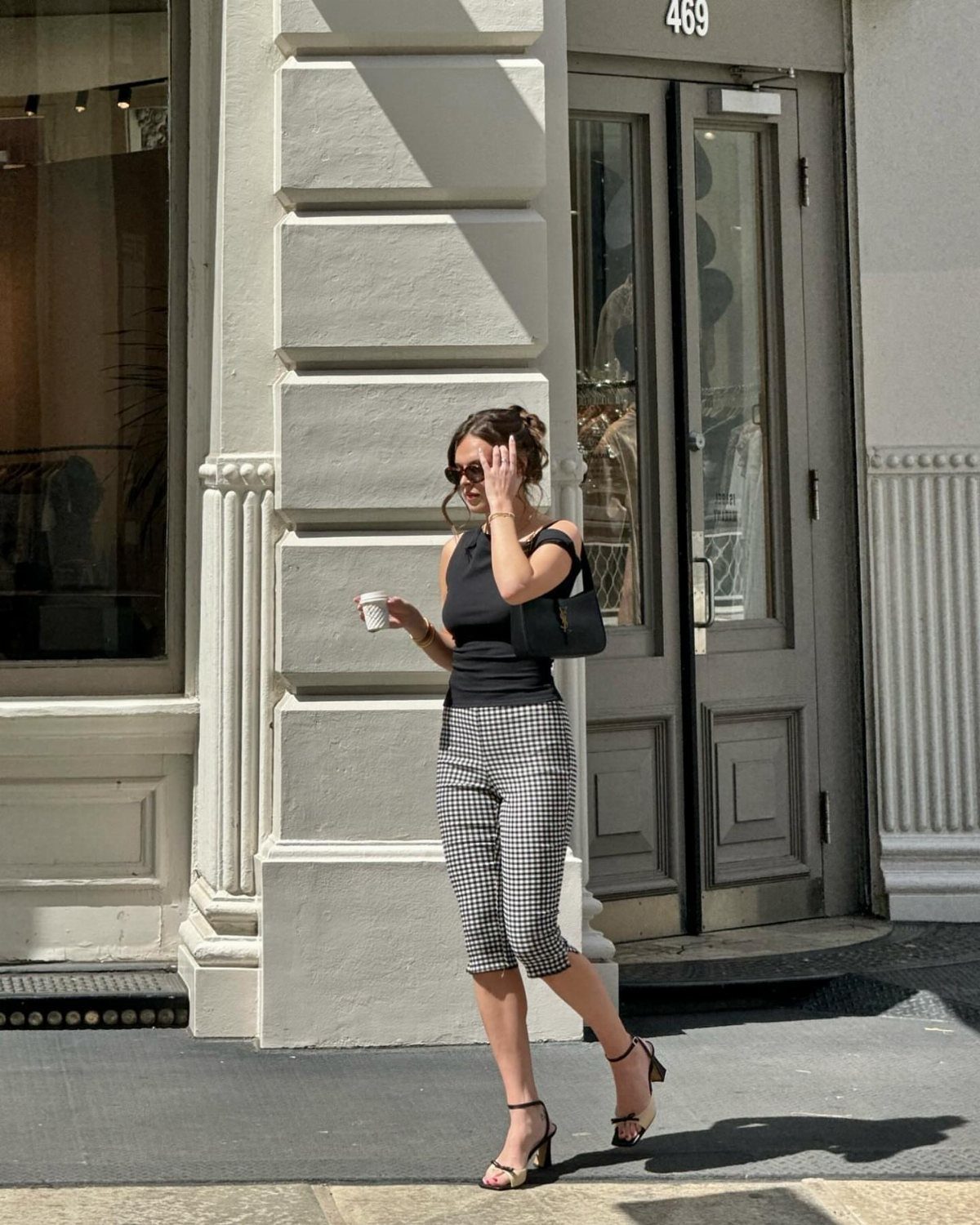 Carrie Bradshaw Outfits: 11 Iconic Looks to Recreate 6 Woman in black top and cropped checkered pants wearing high heels on city street