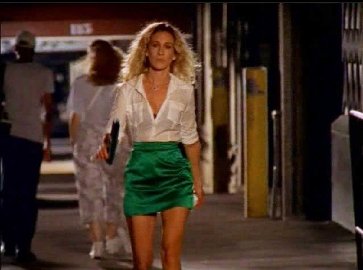 Carrie Bradshaw Outfits: 11 Iconic Looks to Recreate 8 Woman with curly blonde hair wearing a white shirt and green satin mini skirt.