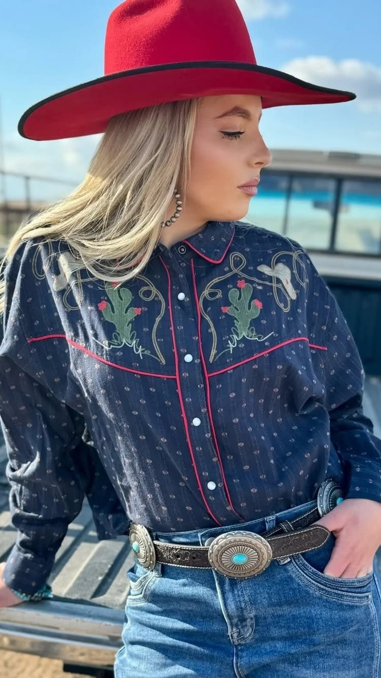 14 Coastal Cowgirl Outfits for Breezy Western Beach Style 4 Woman in red cowgirl hat and embroidered cactus shirt with blue denim jeans.