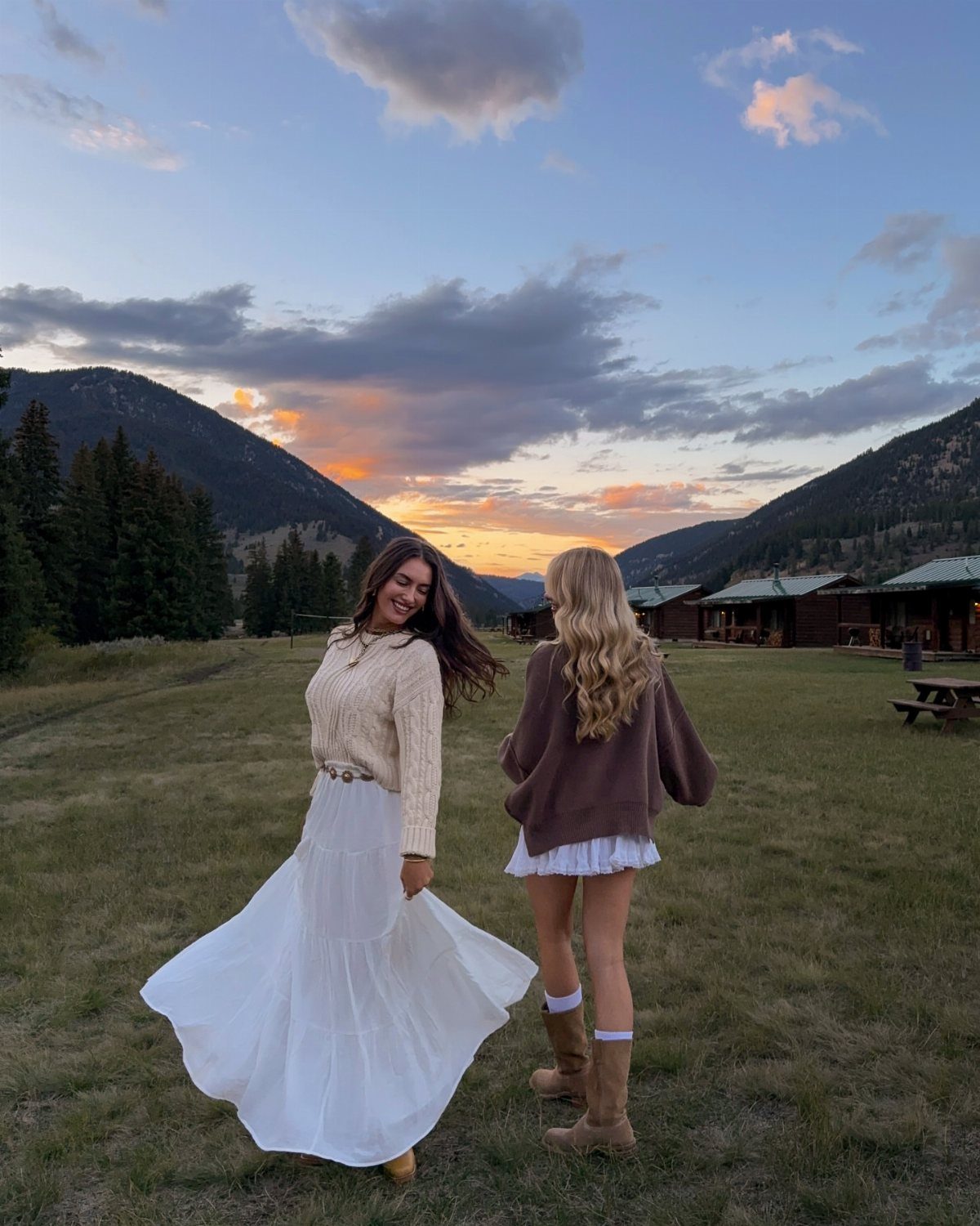 14 Coastal Cowgirl Outfits for Breezy Western Beach Style 1 Woman in a long white flowy skirt and brown boots in a mountain field.