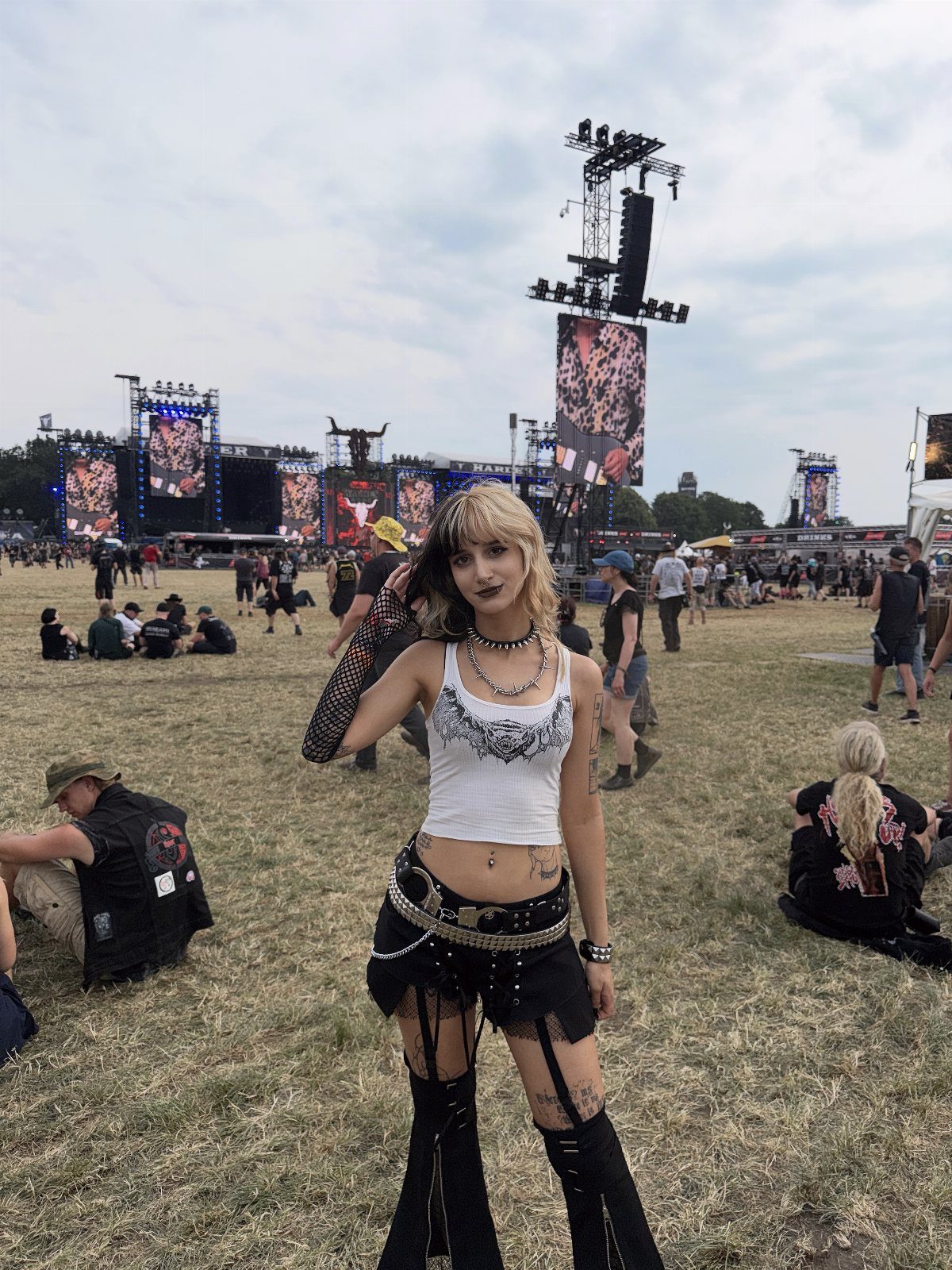 Concert Outfits for Women: 8 Looks That Work for Any Venue 1 Woman in edgy concert attire with a white crop top and black studded accessories.