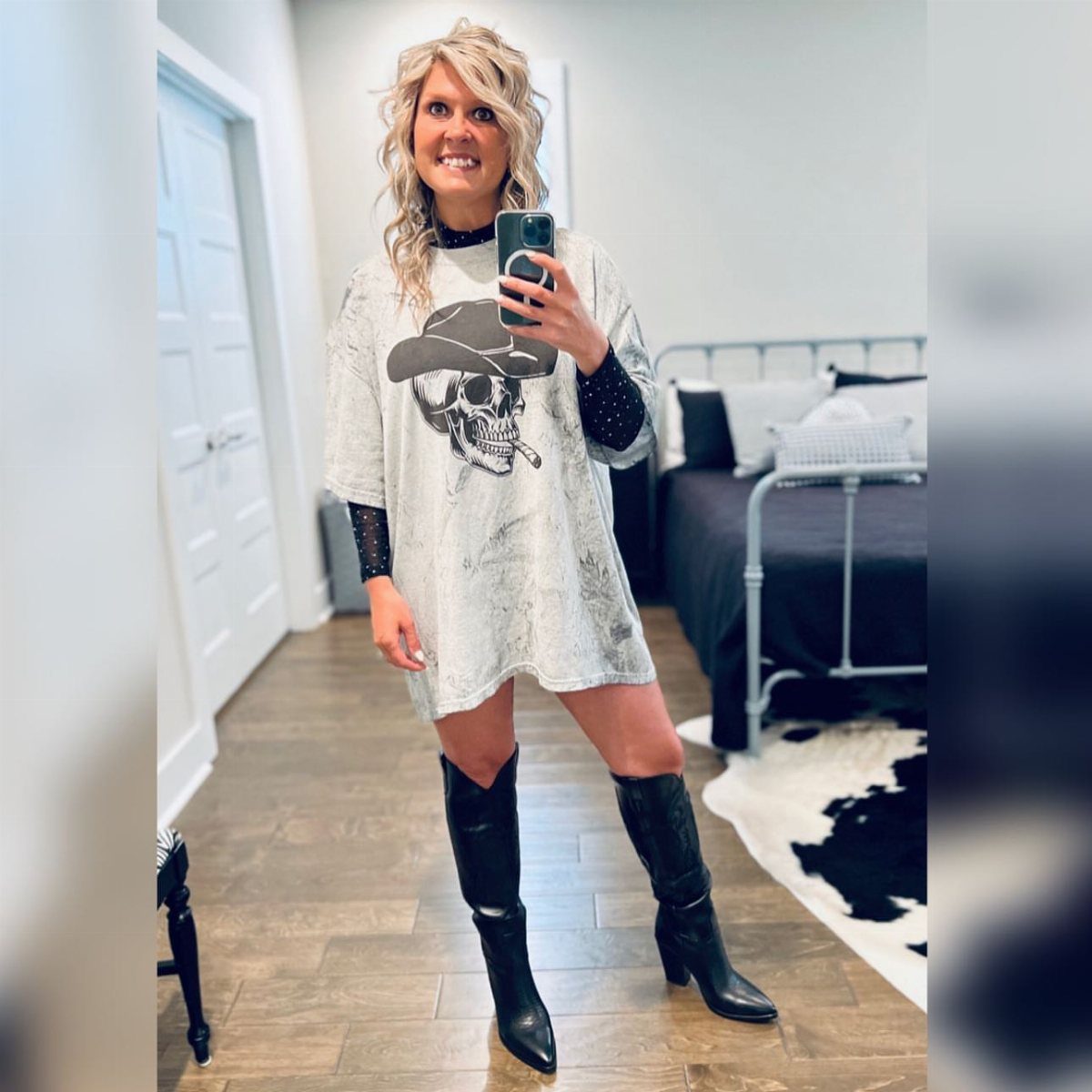 Concert Outfits for Women: 8 Looks That Work for Any Venue 2 Woman wearing a skull graphic t-shirt and black cowboy boots in a bedroom.