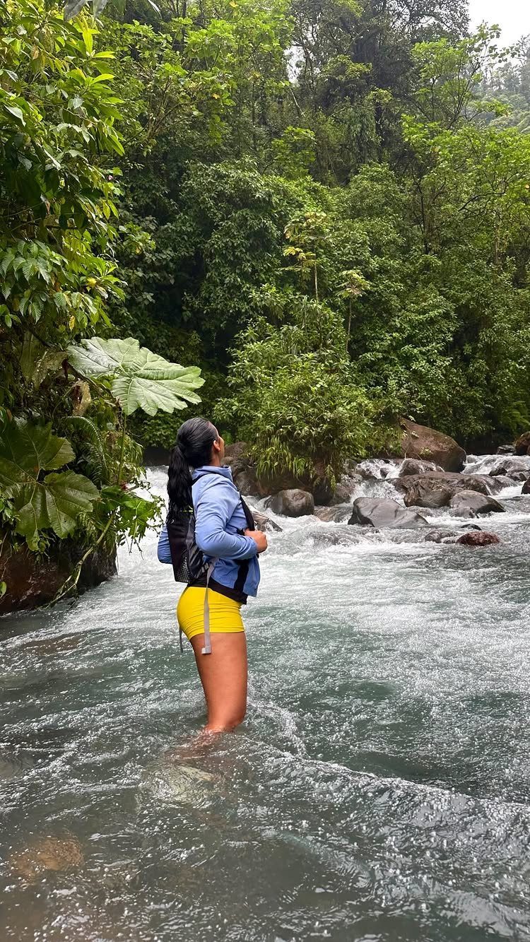 Costa Rica Outfits: 10 Ideas for Your Trip 8 Woman in blue jacket and yellow shorts standing in a tropical river.