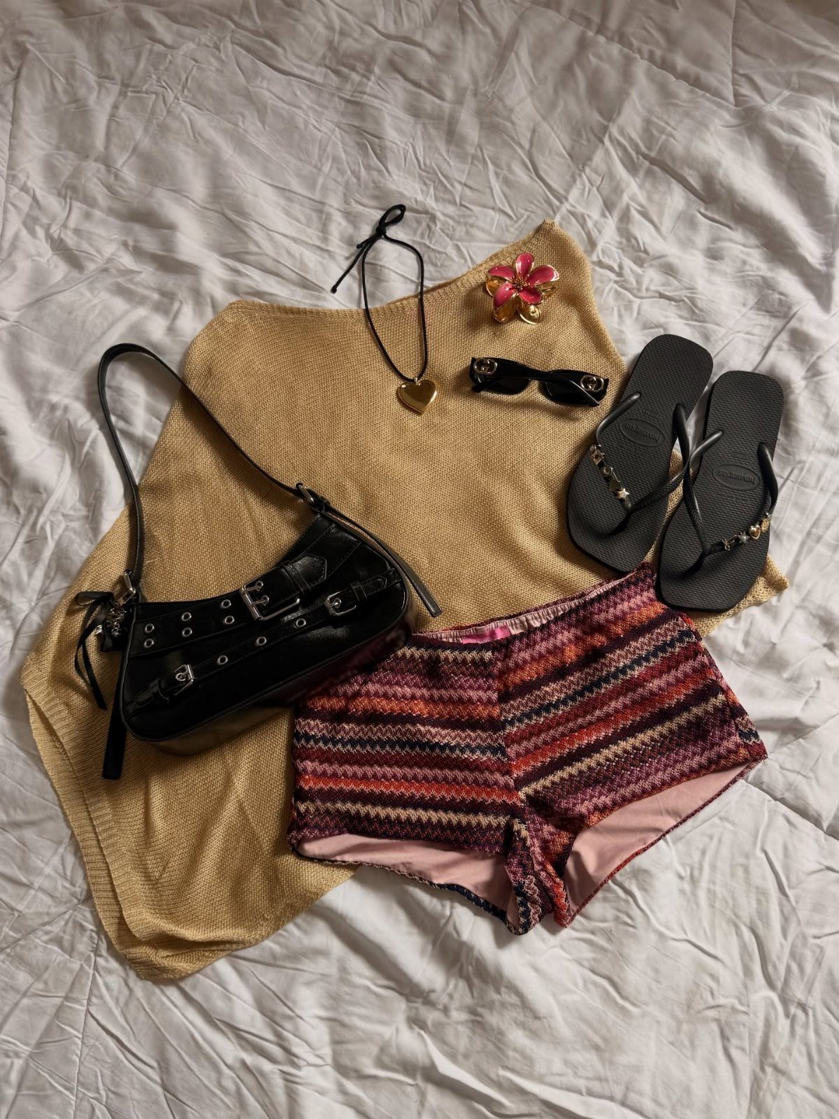 Costa Rica Outfits: 10 Ideas for Your Trip 10 Vacation outfit flat lay with tan cover-up, patterned shorts, flip-flops, and black accessories.