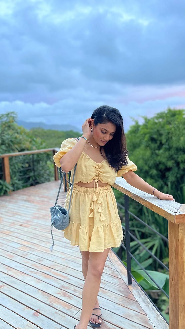 Costa Rica Outfits: 10 Ideas for Your Trip 4 Woman in a yellow two-piece set and crossbody bag on a wooden deck.