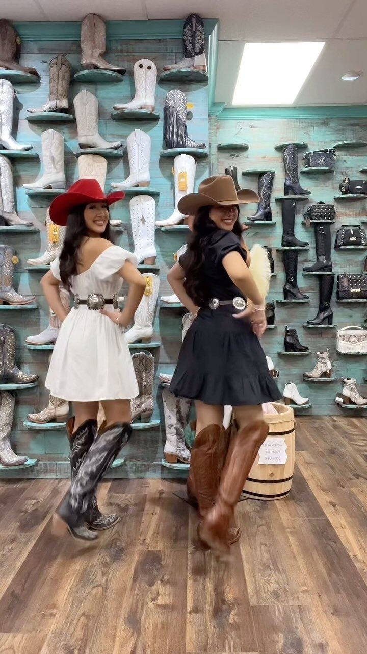 10 Cute Country Outfits with Denim, Boots, and Fringe 3 Two women wearing western dresses, cowboy hats, and boots in a boot store.