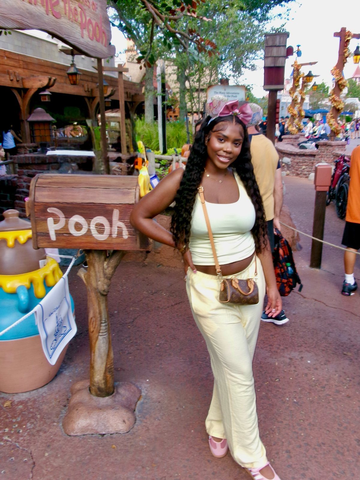 10 Cute Disney Outfits to Wear at the Parks in 2026 4 Woman in a yellow matching set and pink Minnie ears posing at Disney World.