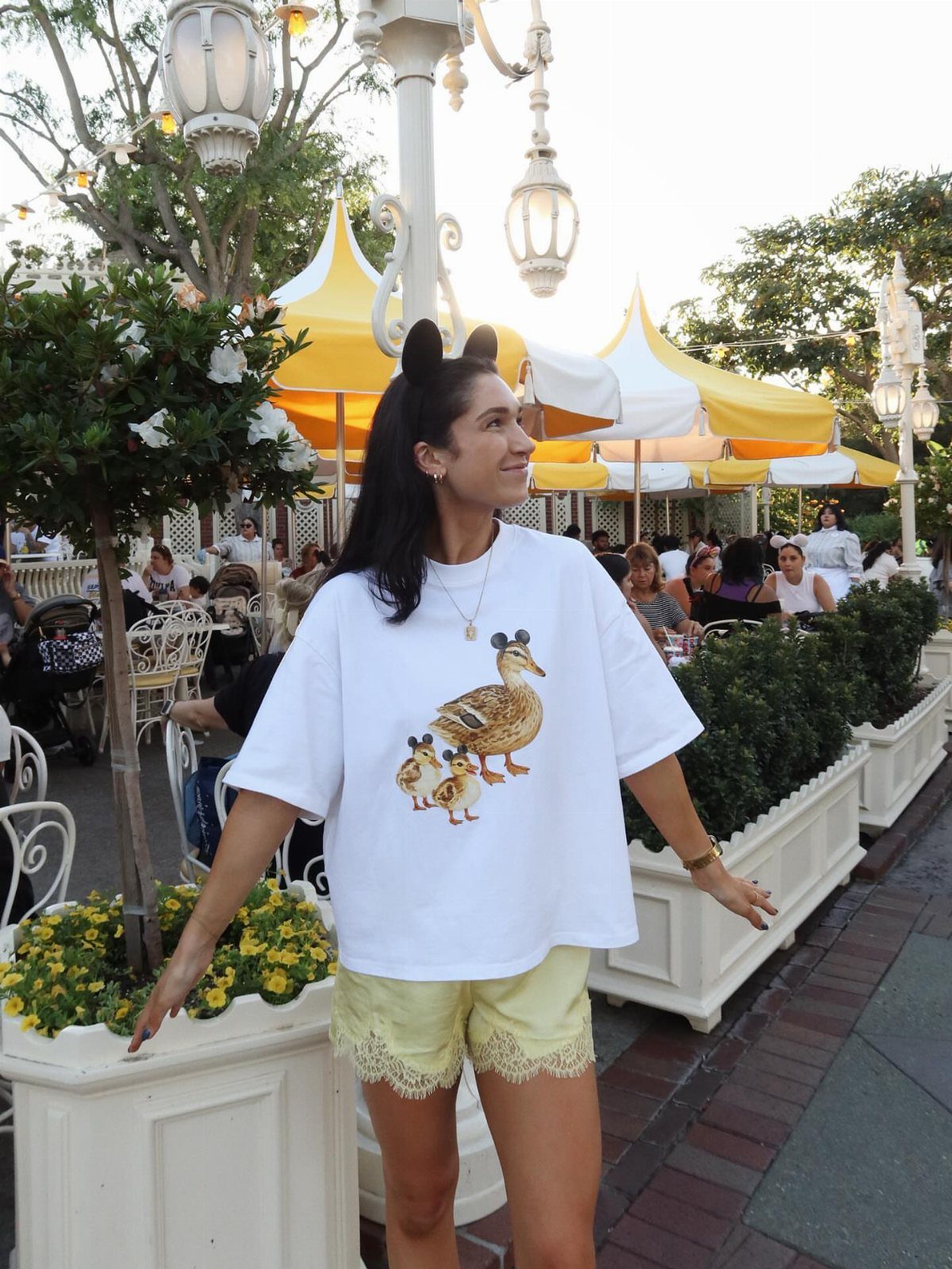 10 Cute Disney Outfits to Wear at the Parks in 2026 10 Woman in white duck t-shirt and yellow shorts wearing Mickey ear headbands.