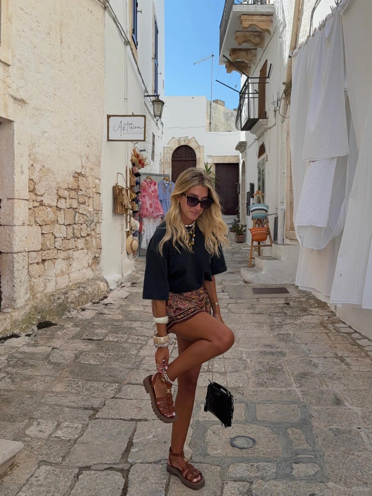 12 Cute Summer Outfits to Keep You Cool and Stylish 11 Woman in a black top and brown skirt wearing brown platform sandals in a street.
