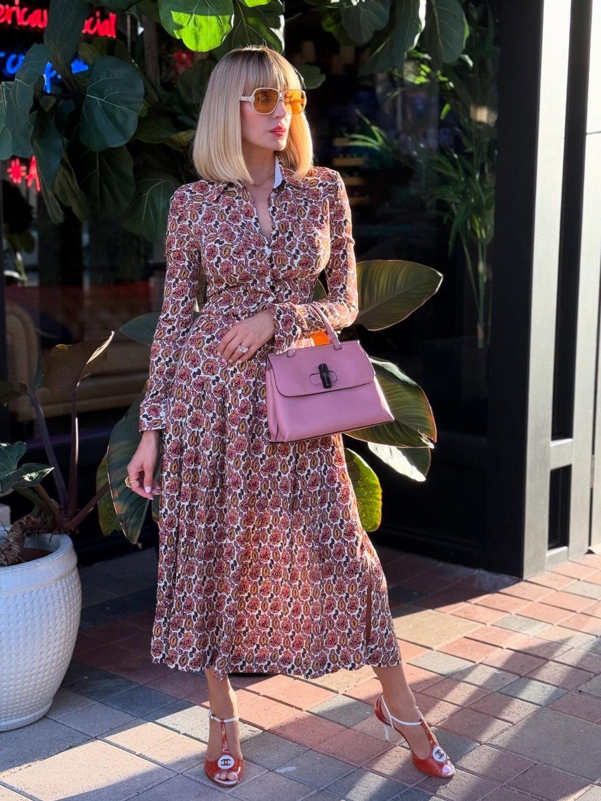 12 Cute Summer Outfits to Keep You Cool and Stylish 1 Woman wearing a long-sleeved floral print dress with a pink handbag and red heels.