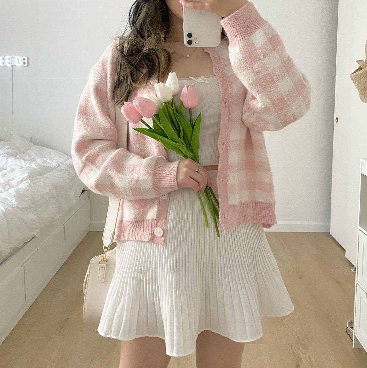 12 Cute Summer Outfits to Keep You Cool and Stylish 4 Person in a pink checkered cardigan and white pleated dress holding tulips.