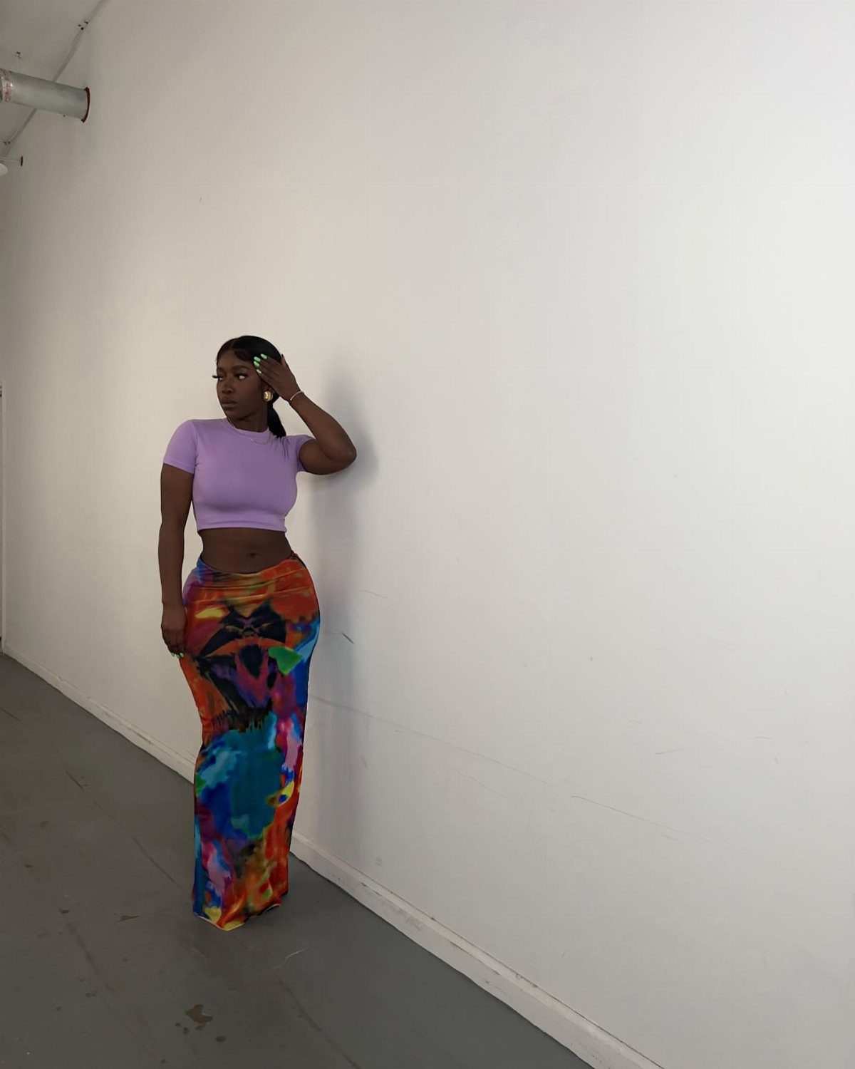 12 Cute Summer Outfits to Keep You Cool and Stylish 9 Woman wearing a purple cropped top and a colorful abstract print maxi skirt.