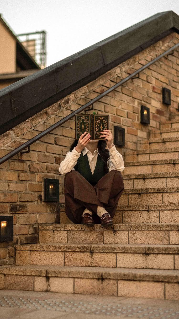 Dark Academia Outfits Female: 12 Ideas for Timeless Style 2 Person in a green sweater vest and collared shirt reading a book on stairs.