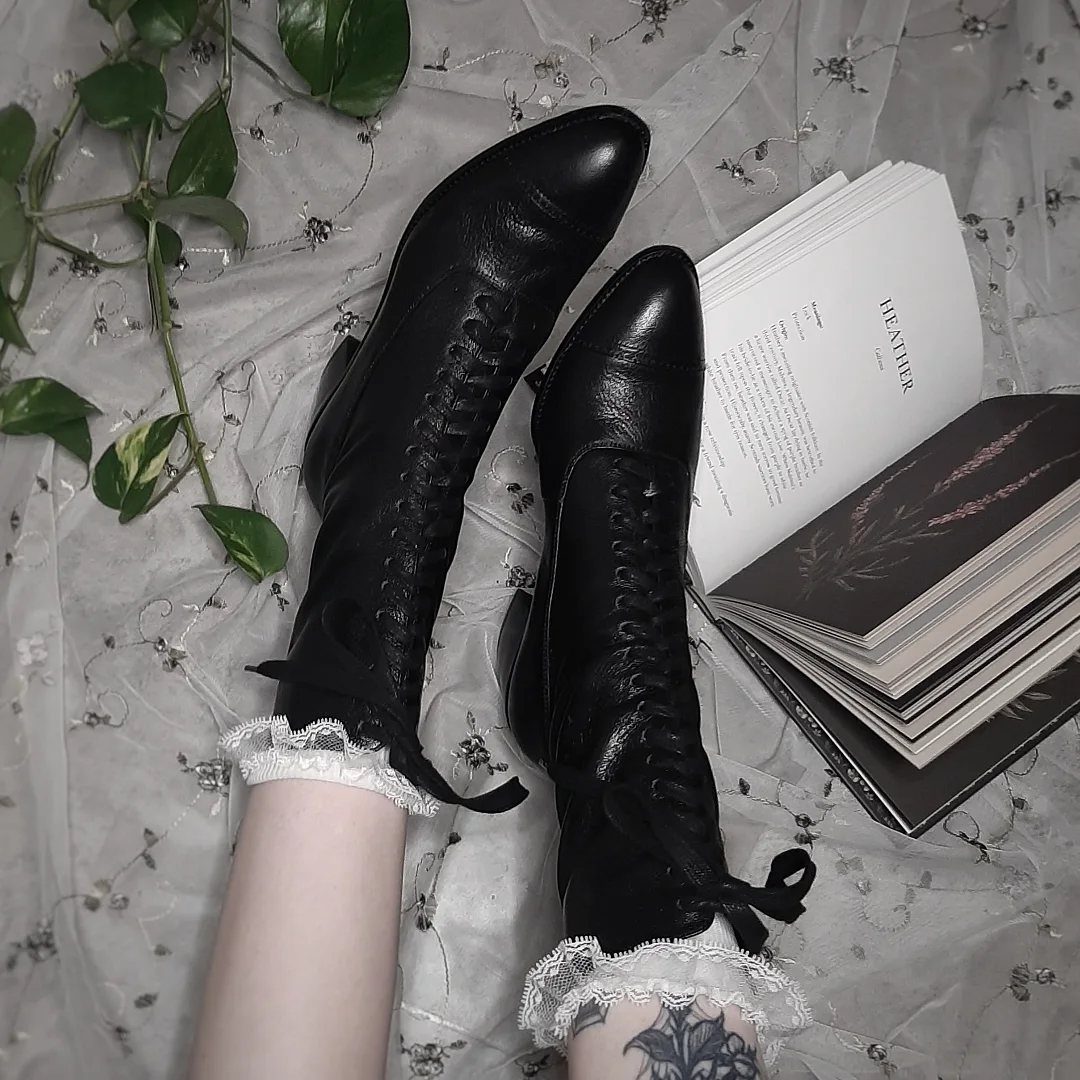 Dark Cottagecore Outfits: 8 Ideas from Dresses to Footwear 2 Black lace-up leather boots with white lace ruffles on a sheer white fabric.