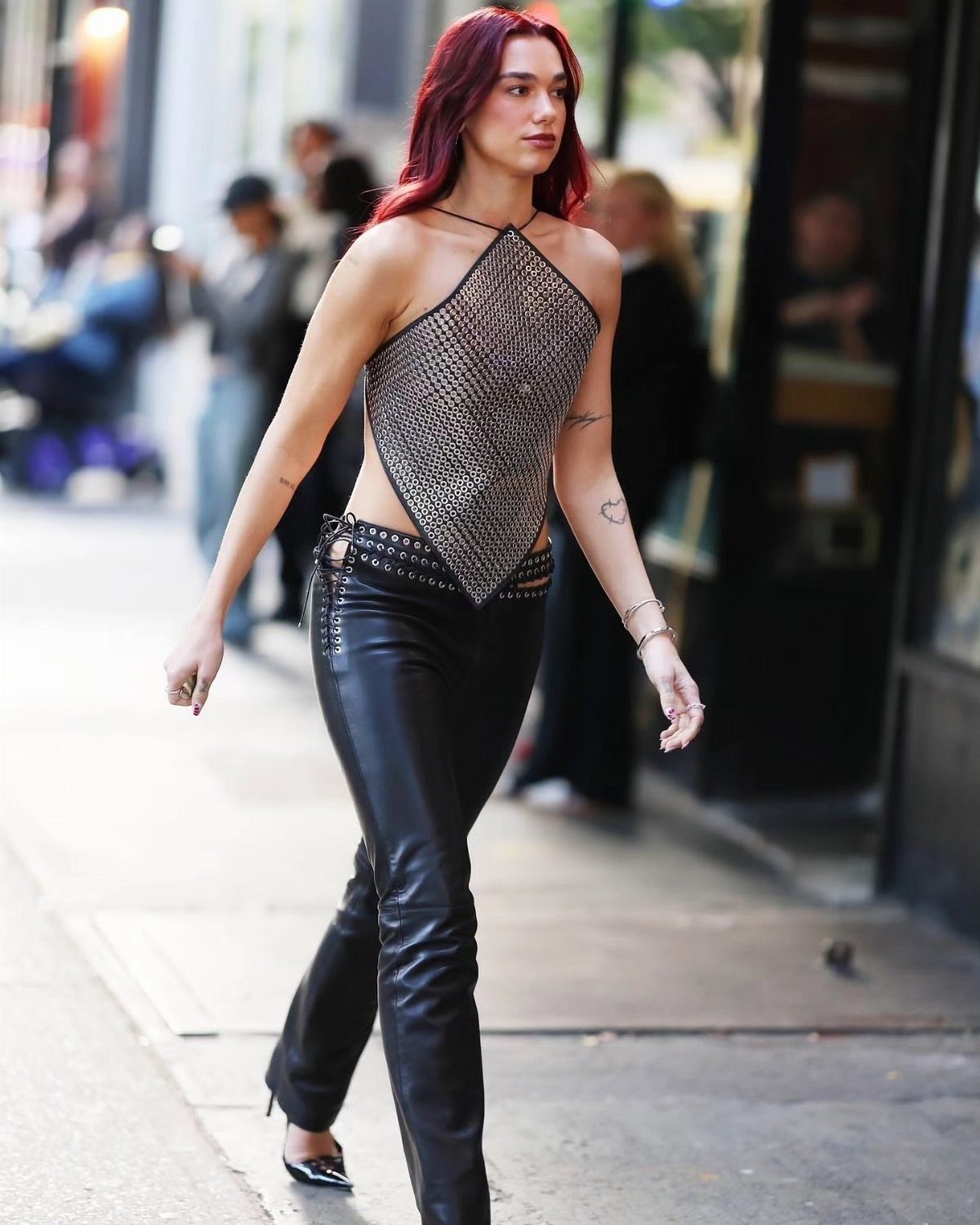 Dua Lipa Concert Outfits: 7 Show-Stopping Looks to Try 2 Woman with red hair wearing a silver chainmail top and black leather pants.