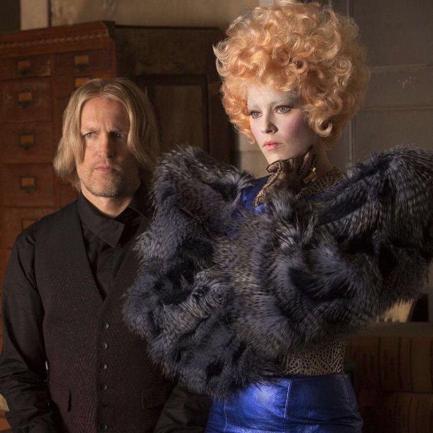 Effie Trinket Outfits: 10 Iconic Looks to Recreate 7 Effie Trinket wearing a voluminous grey fur stole and blue metallic skirt.