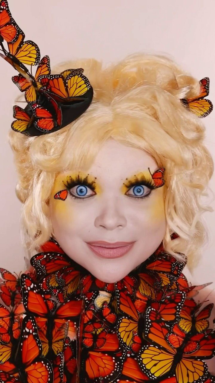 Effie Trinket Outfits: 10 Iconic Looks to Recreate 10 Person in Effie Trinket cosplay with blonde wig and butterfly makeup and outfit