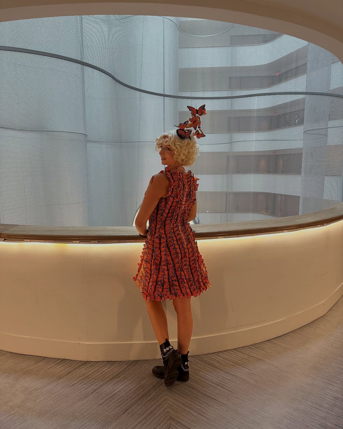 Effie Trinket Outfits: 10 Iconic Looks to Recreate 6 Person in Effie Trinket costume with red patterned dress and blonde curly wig.