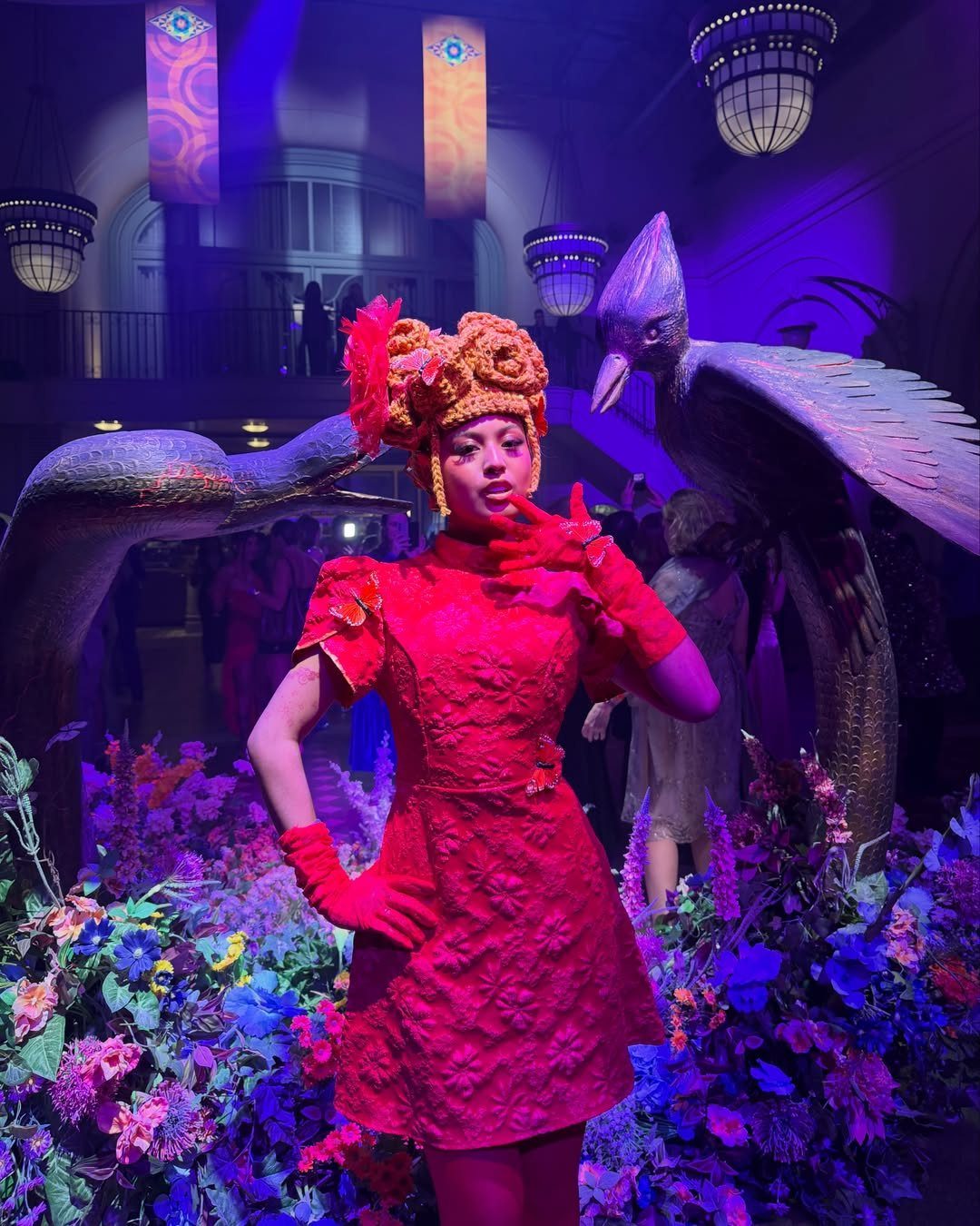 Effie Trinket Outfits: 10 Iconic Looks to Recreate 5 Person in a red Effie Trinket costume with a large ornate headpiece and flowers.