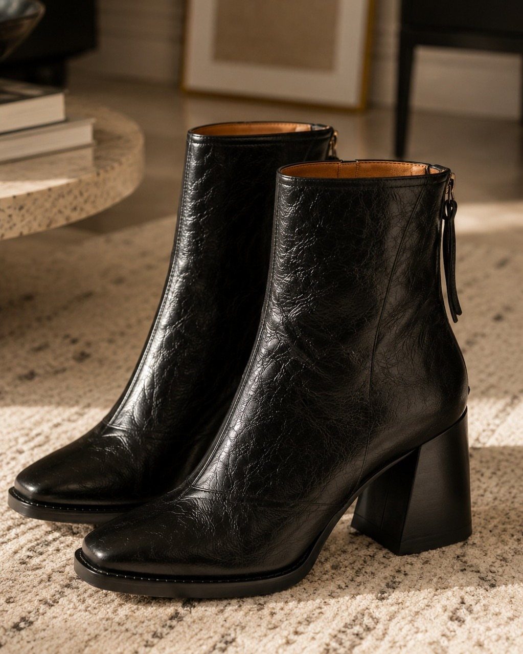 14 Elena Gilbert Outfits: Her Best Looks from the Show 1 Black leather ankle boots with block heels resting on a neutral textured rug.