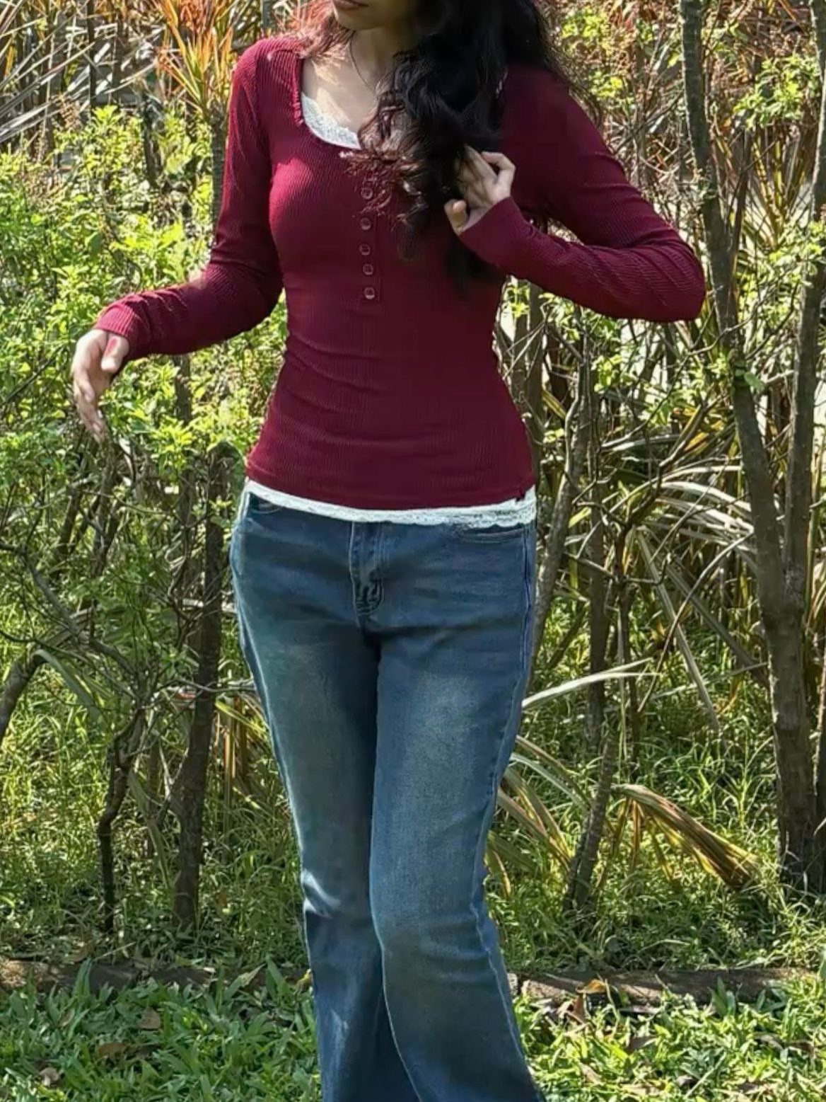 14 Elena Gilbert Outfits: Her Best Looks from the Show 13 Person wearing a maroon henley shirt and blue jeans in a wooded setting.