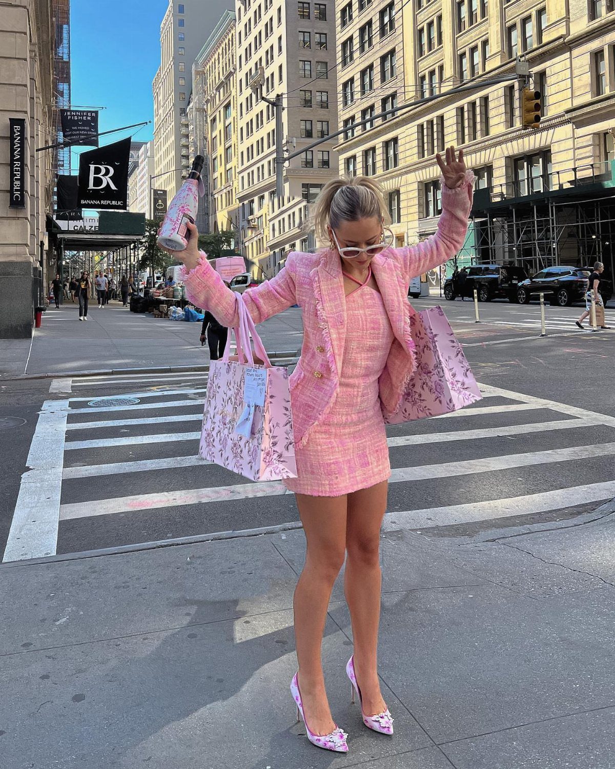 10 Elle Woods Outfits That Defined a Generation of Style 7 Woman in pink tweed blazer and skirt set standing on a city street.