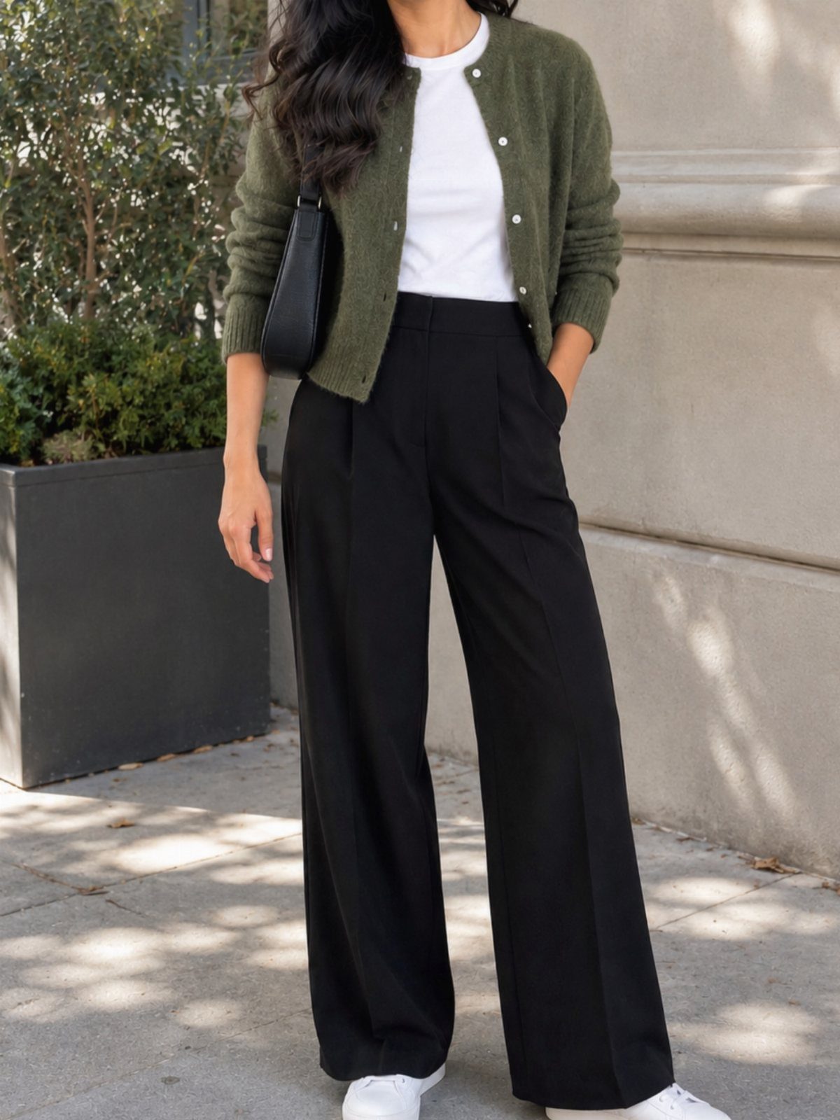Woman wearing an olive green knit cardigan and black wide-leg trousers with white sneakers.