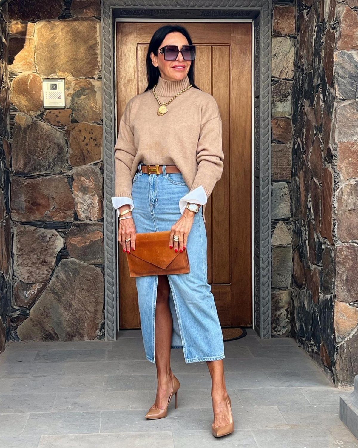 8 Fall Outfits for Women Over 50 to Wear Right Now 1 Woman wearing a tan turtleneck sweater and long blue denim skirt with tan heels.