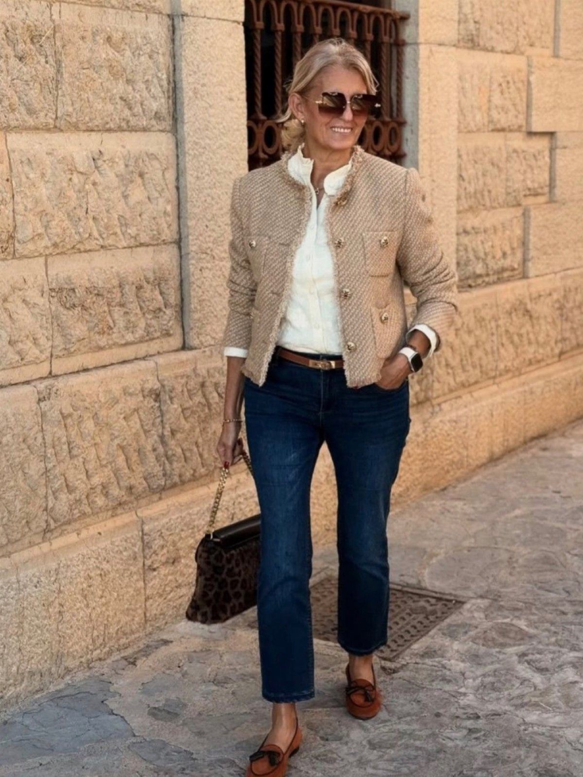 Fall Outfits for Women: 9 Ideas From Denim to Burgundy 1 Woman wearing dark blue denim jeans, a beige jacket, and leopard print handbag.