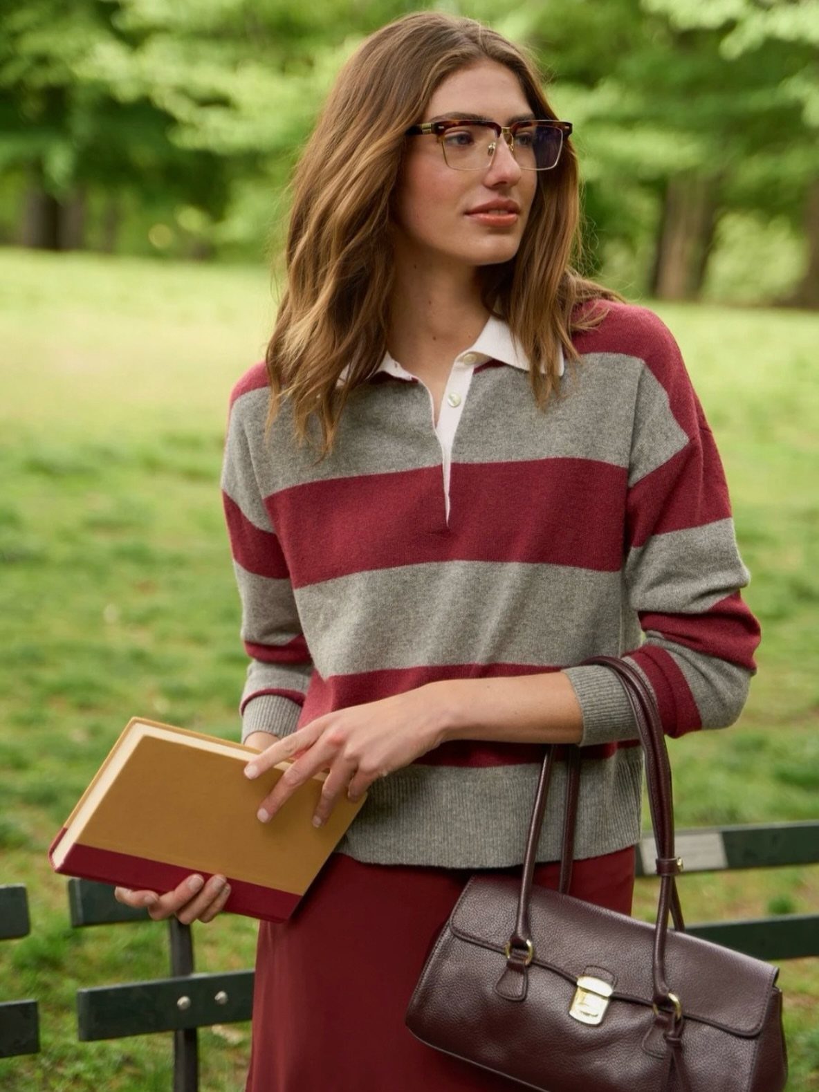 Fall Outfits for Women: 9 Ideas From Denim to Burgundy 4 Woman wearing a striped rugby polo shirt and red midi skirt in a park.