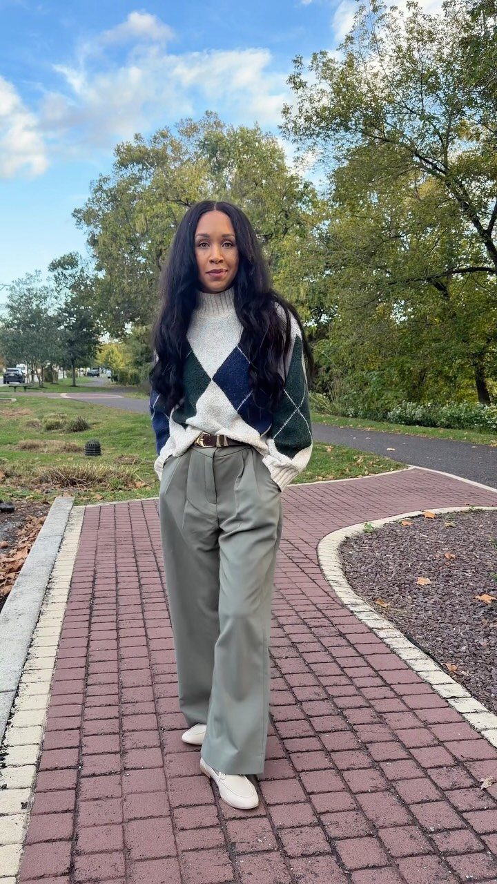 Fall Outfits for Women: 9 Ideas From Denim to Burgundy 5 Woman wearing an argyle sweater and olive green tailored wide-leg pants on a path.