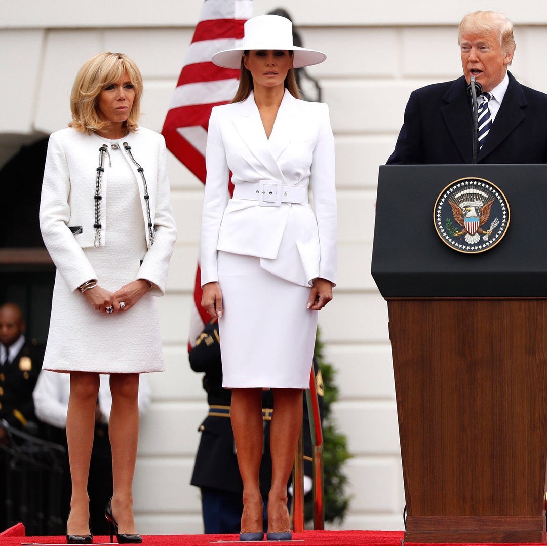 First Lady Outfits: 6 Timeless Looks to Inspire Your Style 4 Melania Trump wearing a white belted dress and wide-brimmed hat at a podium